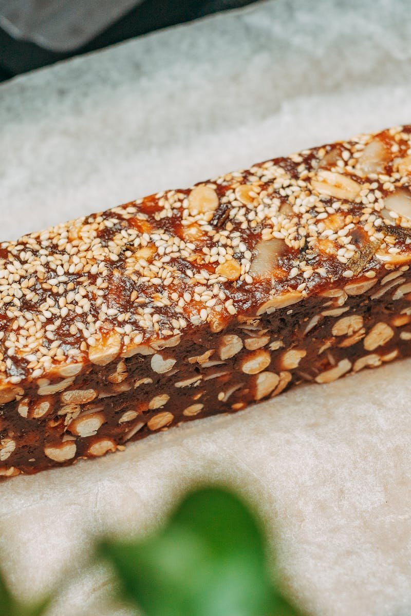 Close-up image of a nut and sesame seed protein bar on parchment paper, ideal for healthy snacking.