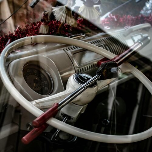 Close-up of a classic car's steering wheel with an anti-theft lock.