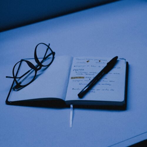 An open notebook with a pen and eyeglasses on a desk, capturing the essence of studying or planning.